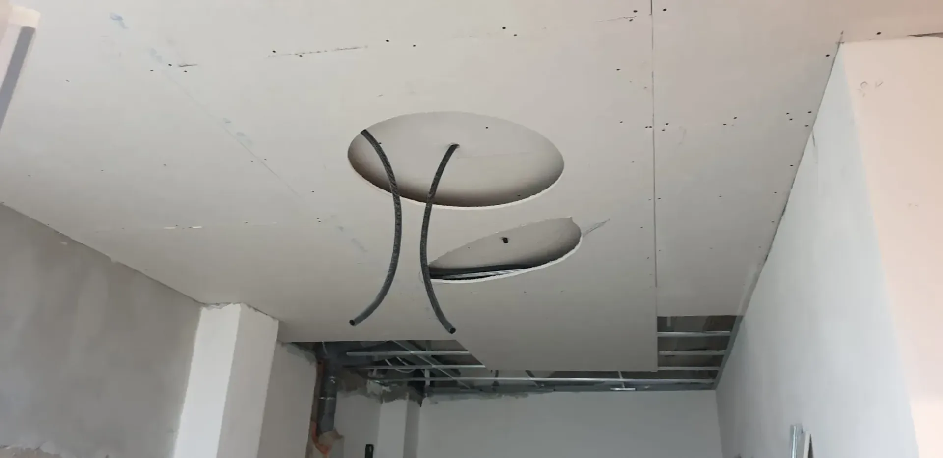 Lámpara ovalada metálica de techo en una habitación blanca y sencilla en construcción