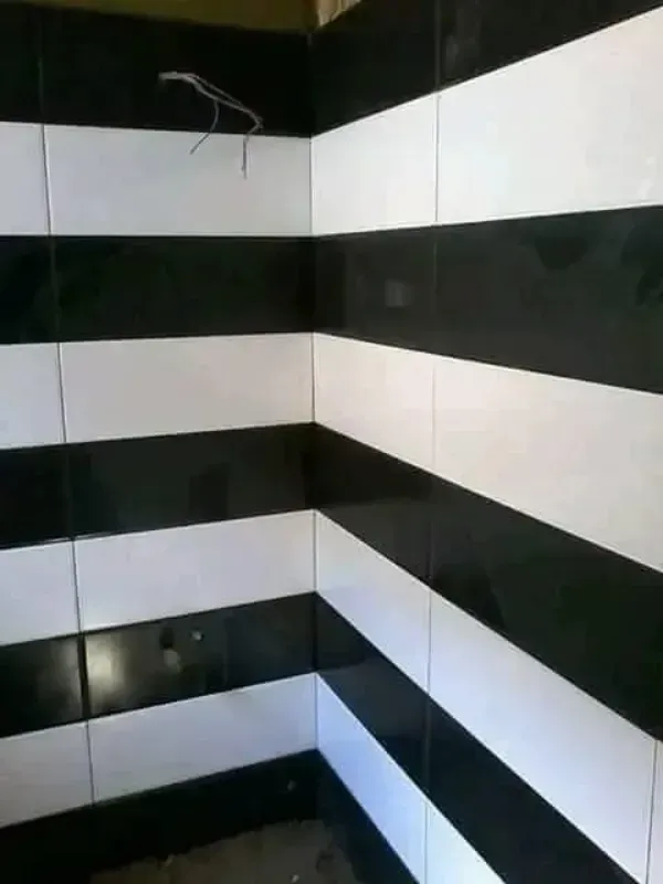 Esquina alicatada en blanco y negro de una habitación vacía o zona de ducha