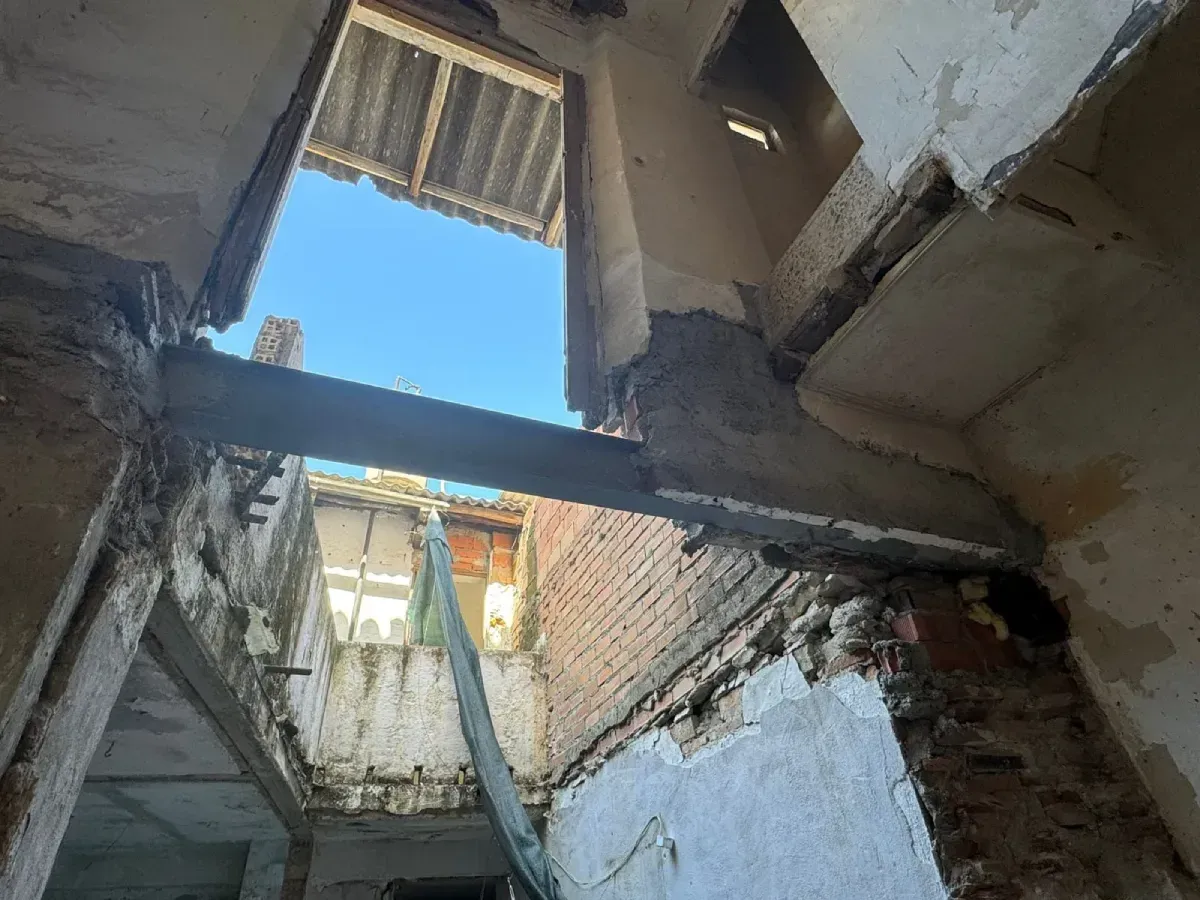 Patio interior dañado, con muros derruidos, ladrillos a la vista y vistas al cielo azul.
