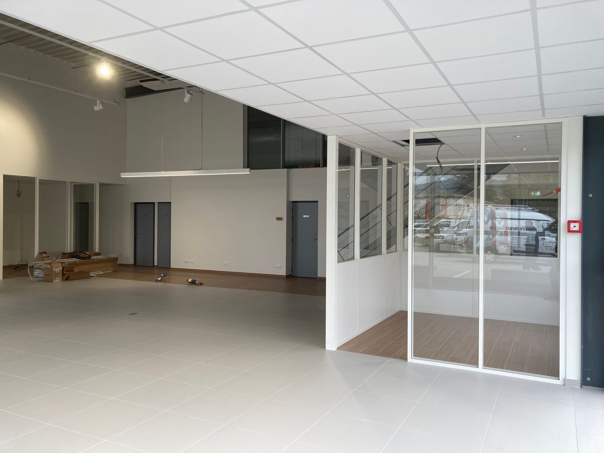 Intérieur d'un local commercial vide, avec murs et plafond blancs et sol gris.