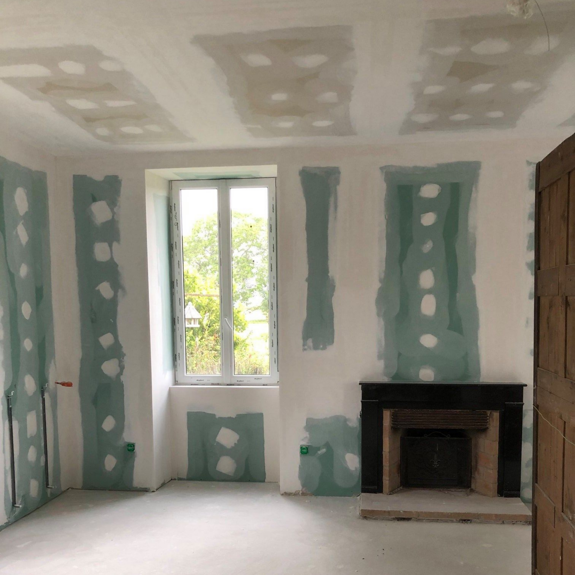 Salle de bains avec meuble-lavabo en bois, miroir rond, baignoire et fenêtre ; tons neutres.