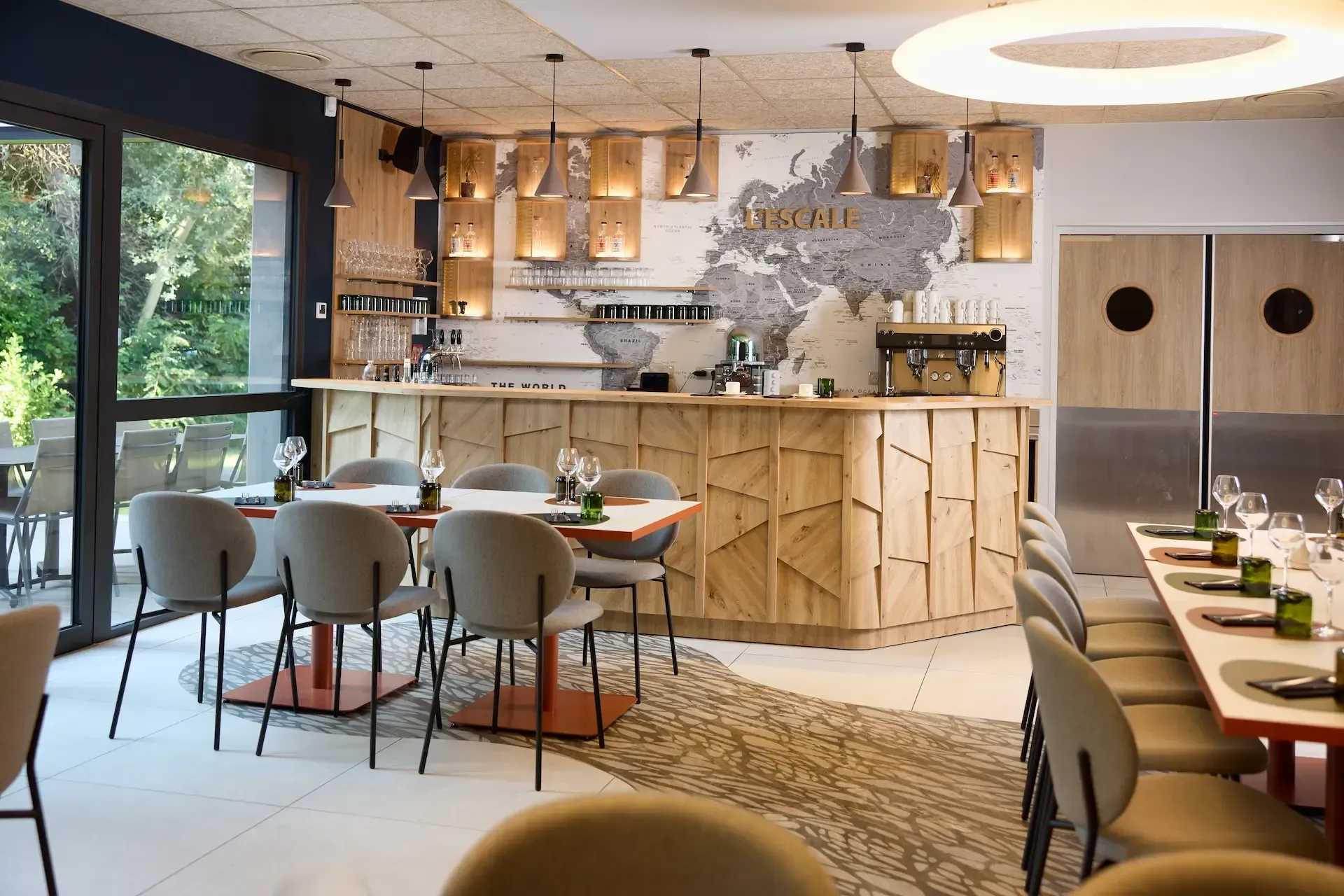 Intérieur de restaurant avec bar en bois, chaises, tables et carte en arrière-plan.