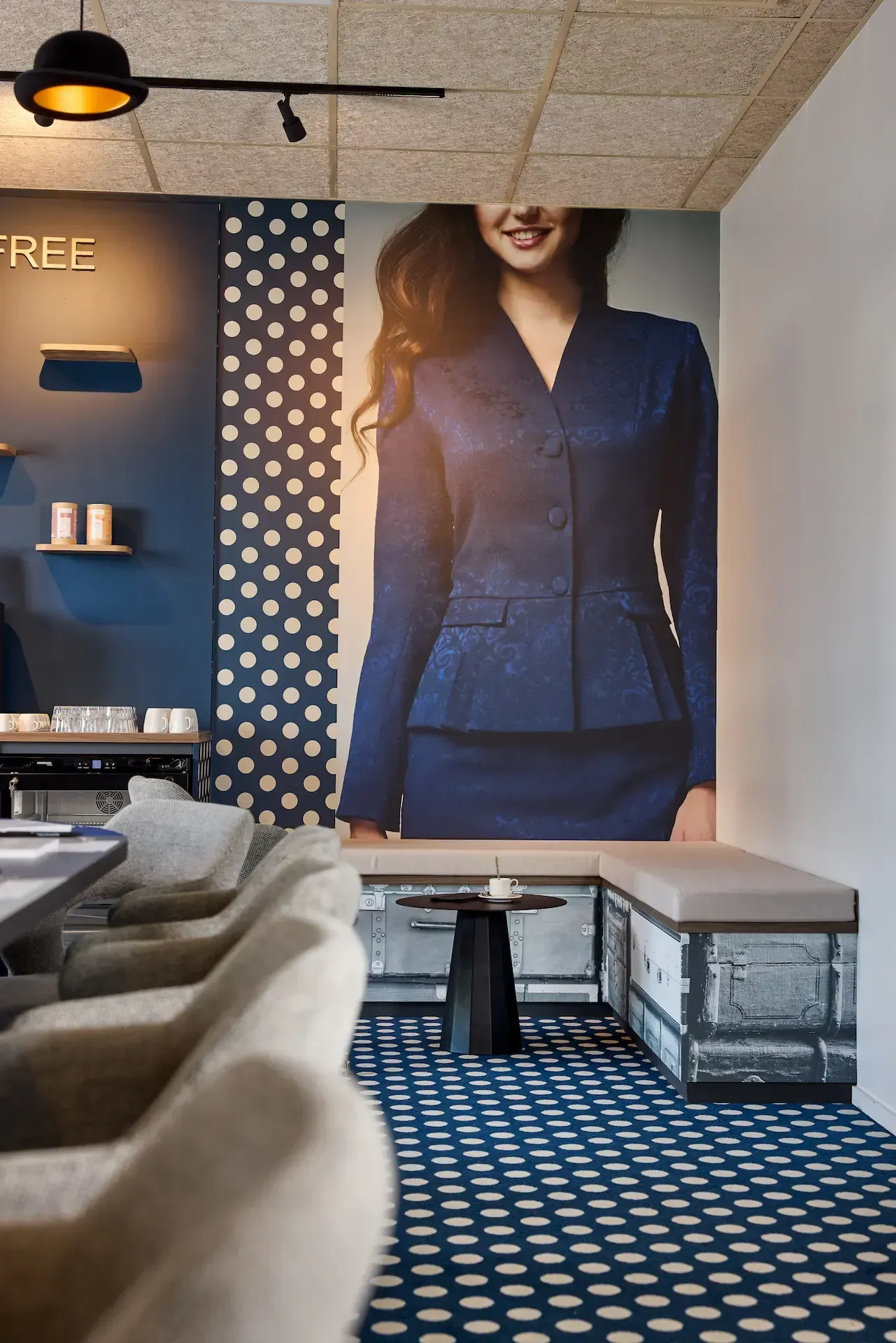 Intérieur avec une publicité pour des tailleurs féminins, murs et sol à motifs bleus, coin salon.