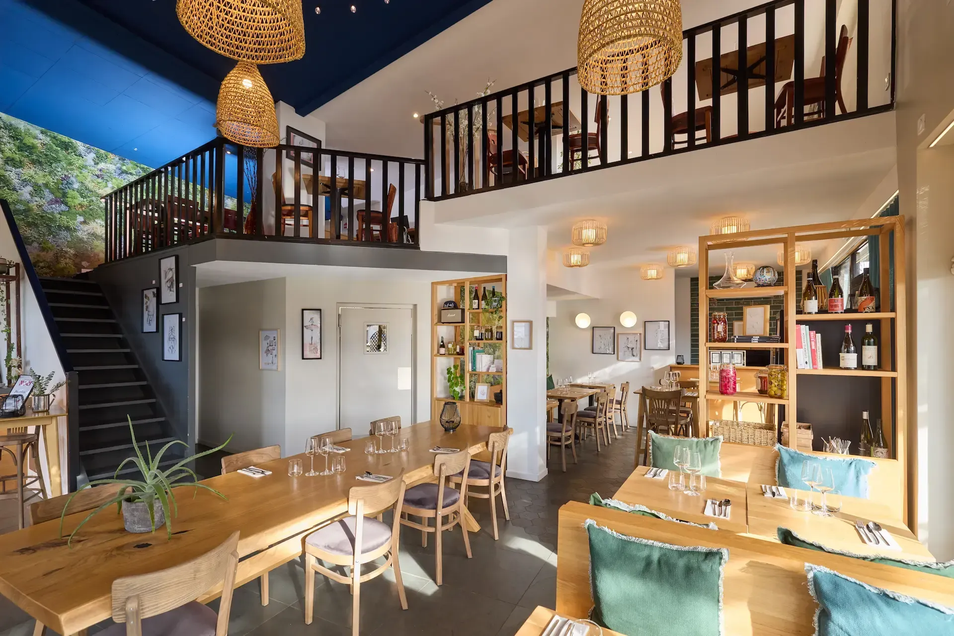 Intérieur d'un restaurant avec mezzanine. Tables et chaises sont disposées, ainsi que des étagères présentant divers articles.
