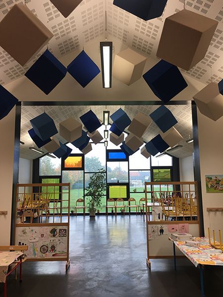 Intérieur d'une pièce avec des cubes bleus et beiges flottants, une grande fenêtre et un sol brillant.