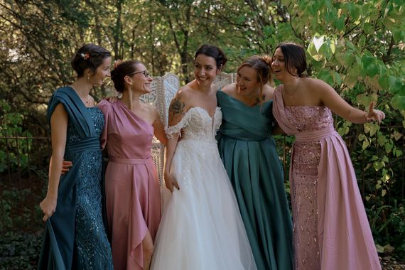 La mariée et ses demoiselles d'honneur, souriantes, vêtues de robes turquoise et roses, en extérieur.