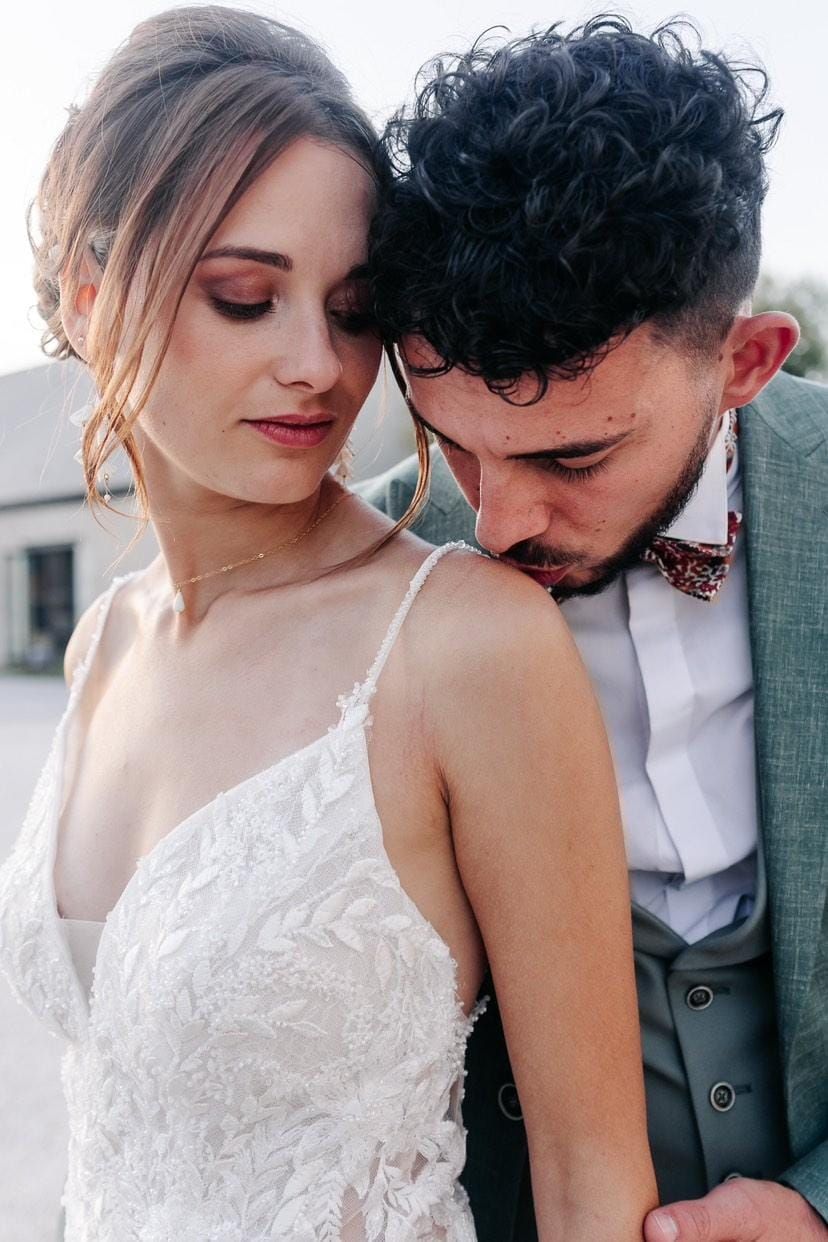 Les mariés s'enlacent, le marié embrassant l'épaule de la mariée.