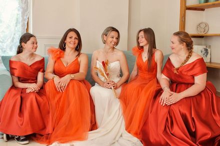 Intérieur de boutique de mariage avec robes de mariée, coin salon, grand miroir et sol carrelé.