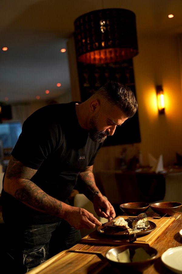 Ein Koch richtet Speisen an einer warm beleuchteten Restauranttheke an.