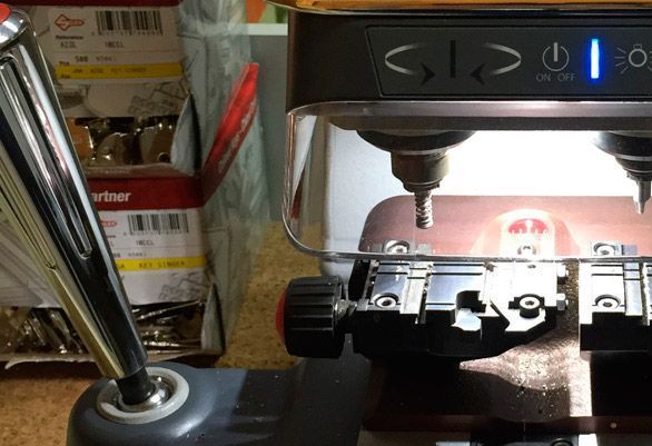 Una máquina cortadora de llaves tiene una luz azul en la pantalla.