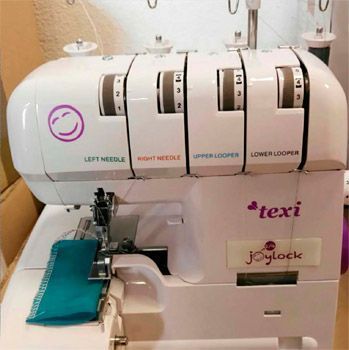 Una máquina de coser Texti Joylock blanca está sobre una mesa.