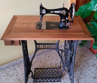 Una vieja máquina de coser Singer se encuentra sobre una mesa de madera.