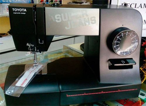 Una máquina de coser Toyota negra se encuentra sobre una mesa de vidrio.
