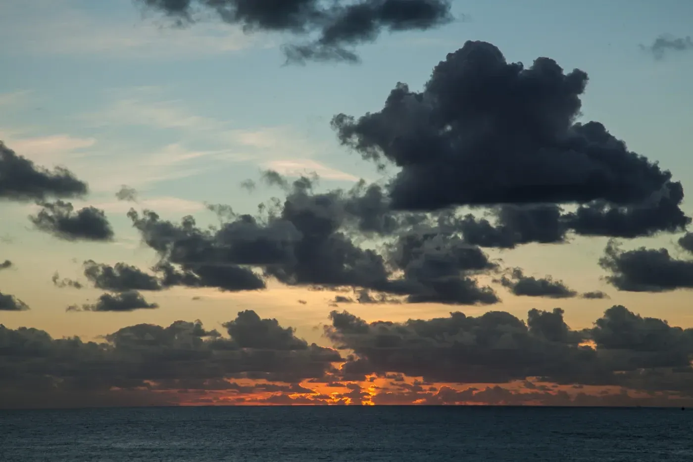Una puesta de sol sobre el océano con nubes en el cielo.