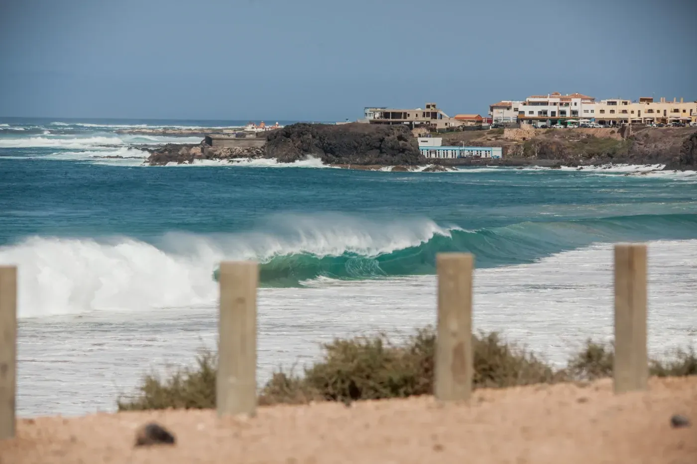Una vista del océano desde una playa con una valla en primer plano.