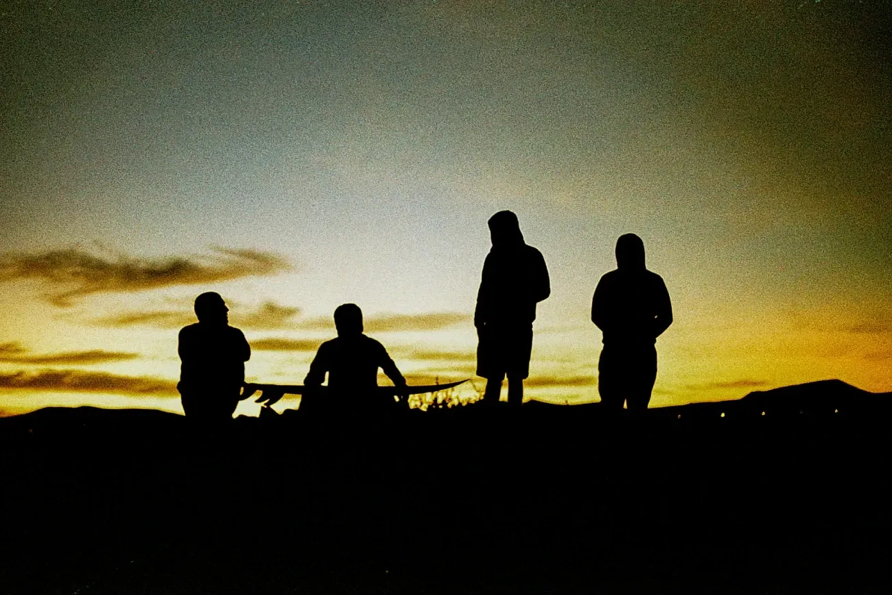 Un grupo de personas de pie en la cima de una colina al atardecer.