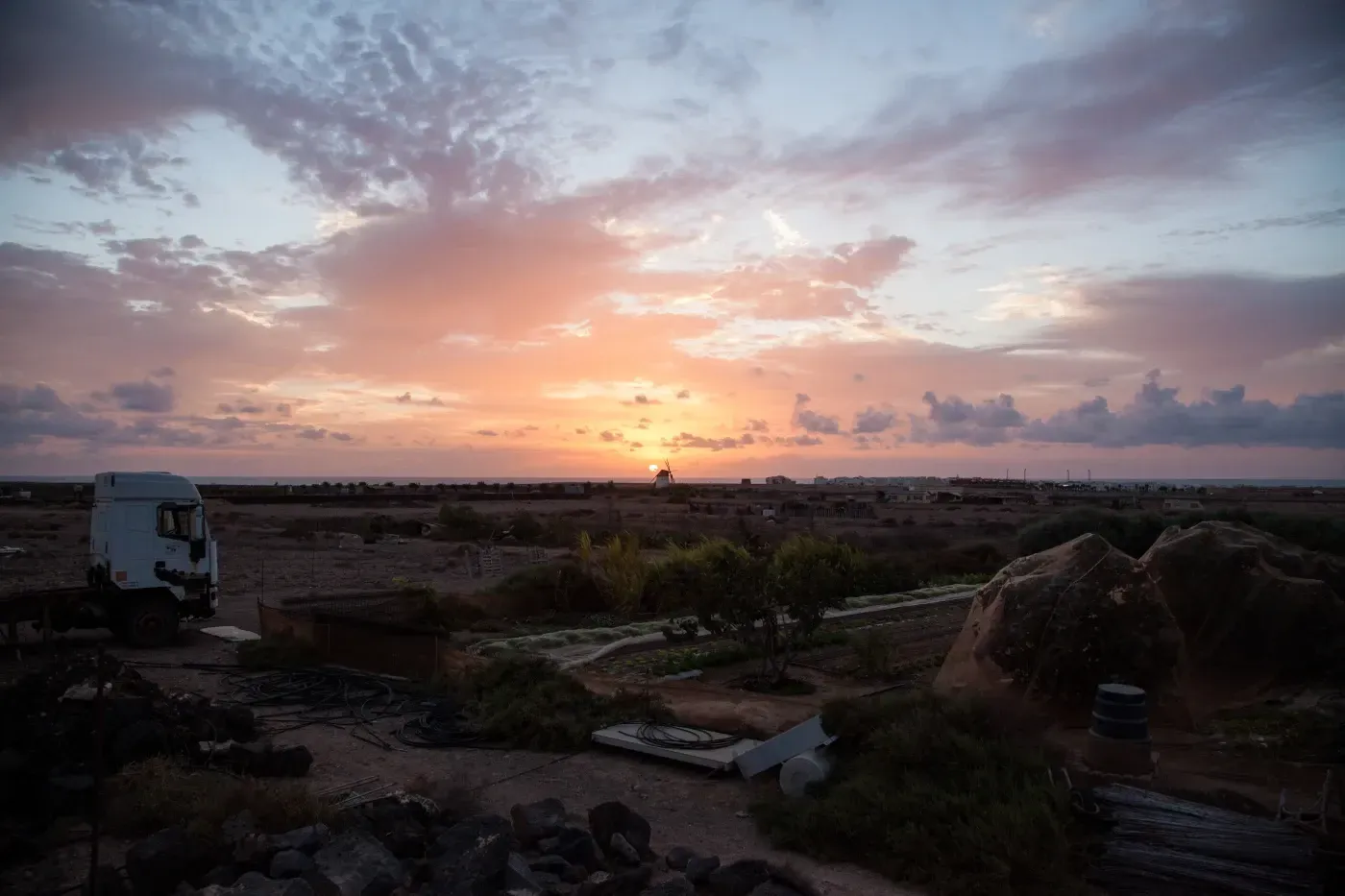 Un camión está estacionado en medio de un campo al atardecer.