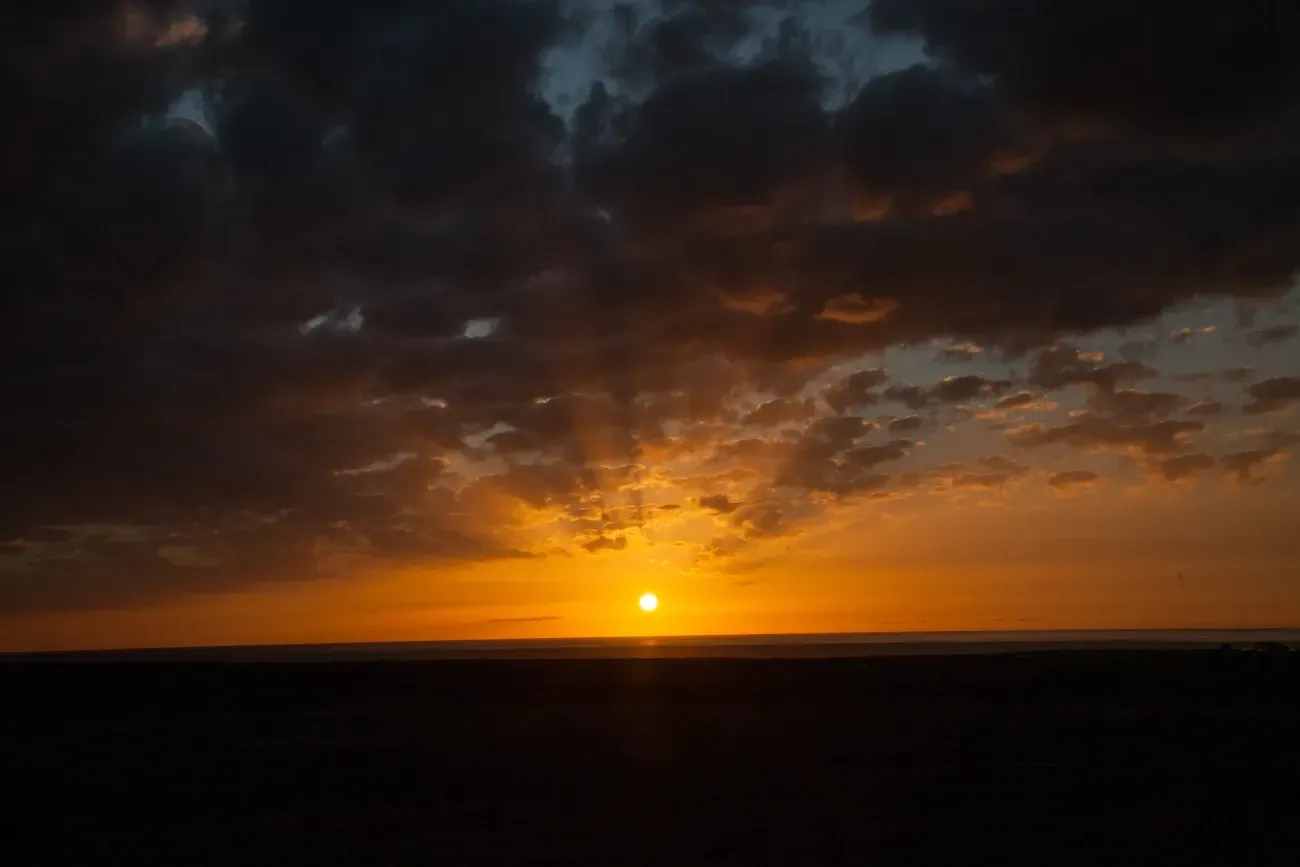 El sol se está poniendo detrás de un cielo nublado sobre el océano.
