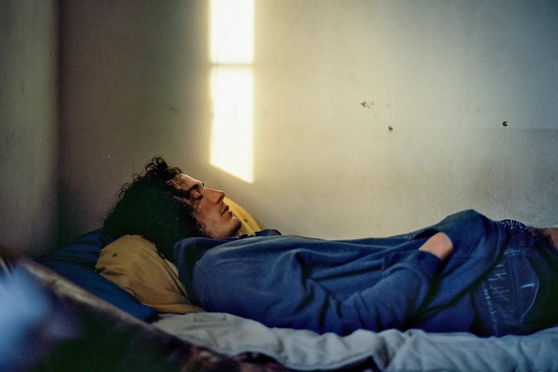 Un hombre está durmiendo en una cama en una habitación oscura.