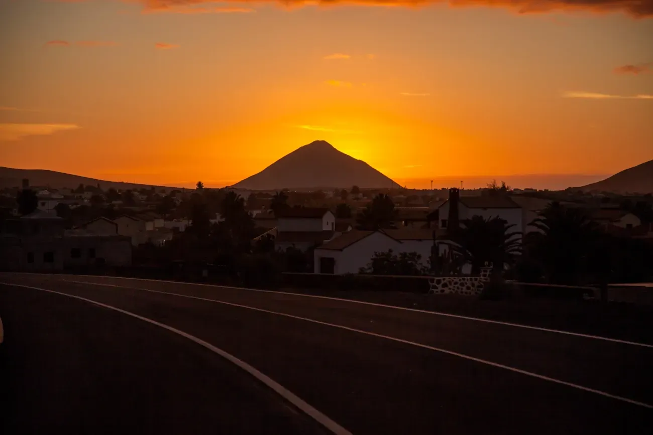 Una puesta de sol sobre una ciudad con una montaña al fondo