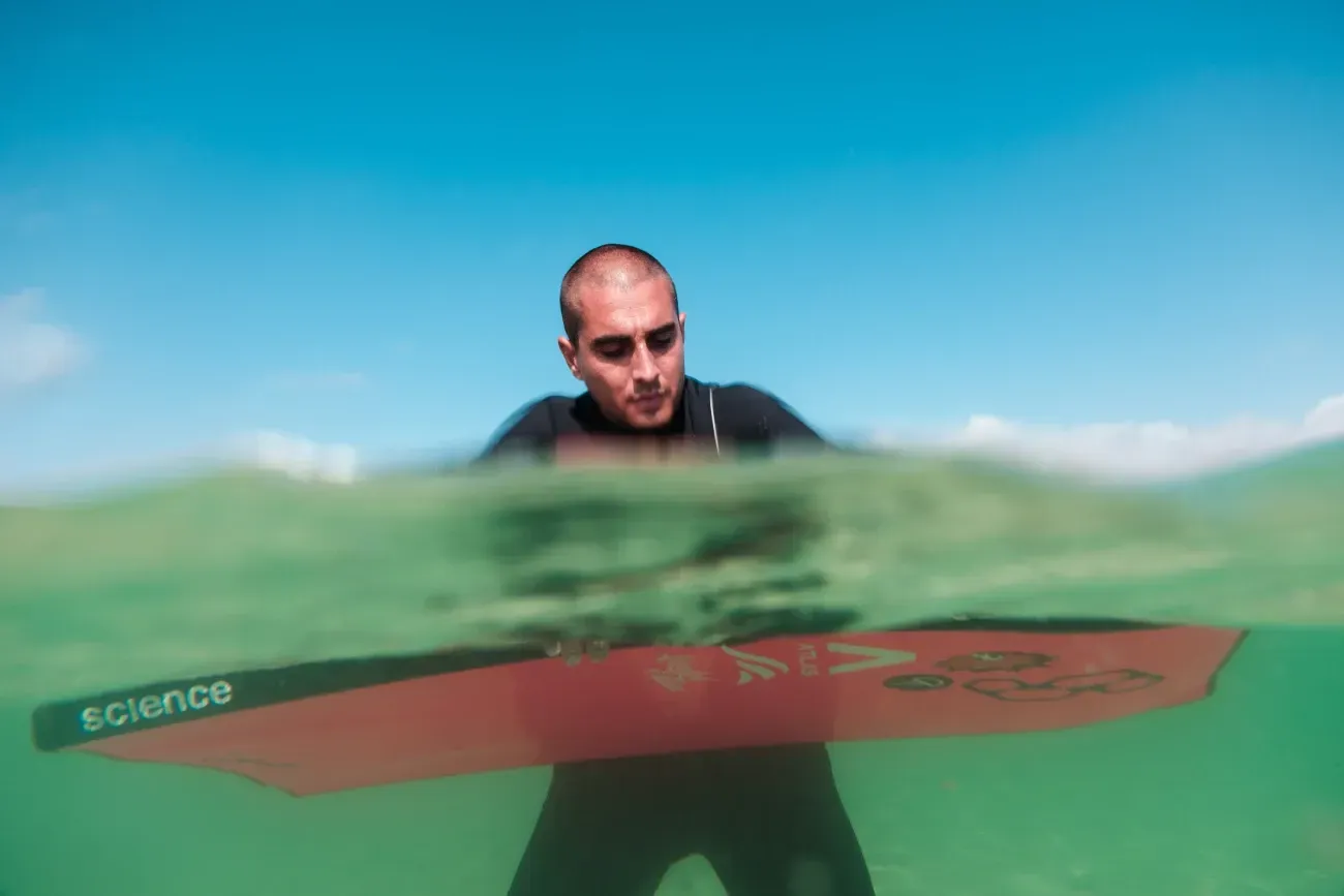 Un hombre está parado en el agua sosteniendo una tabla de surf.