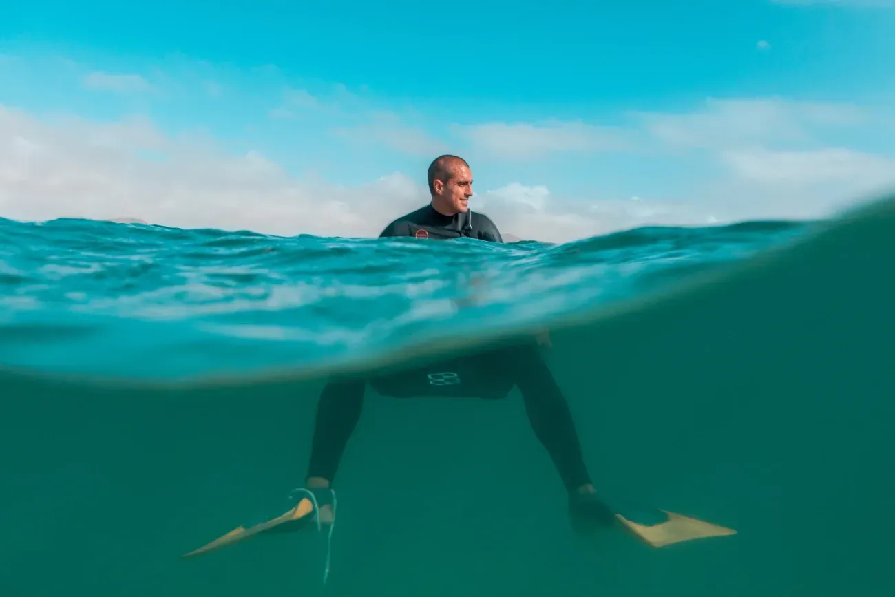 Un hombre está sentado en una tabla de surf en el océano.