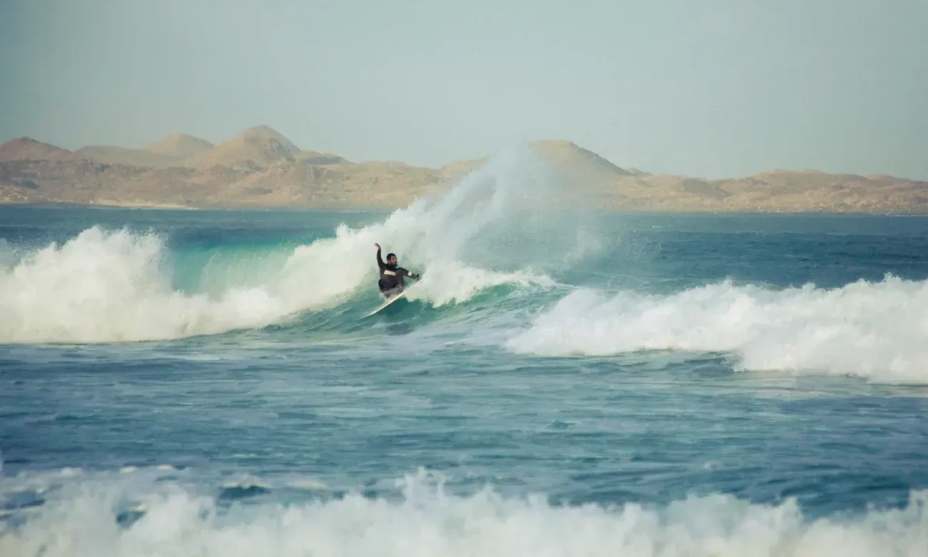 Una persona está montando una ola en una tabla de surf en el océano.