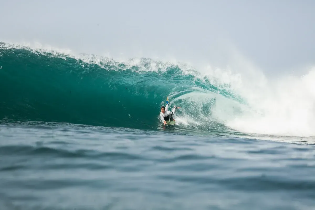 Una persona está montando una ola en una tabla de surf en el océano.