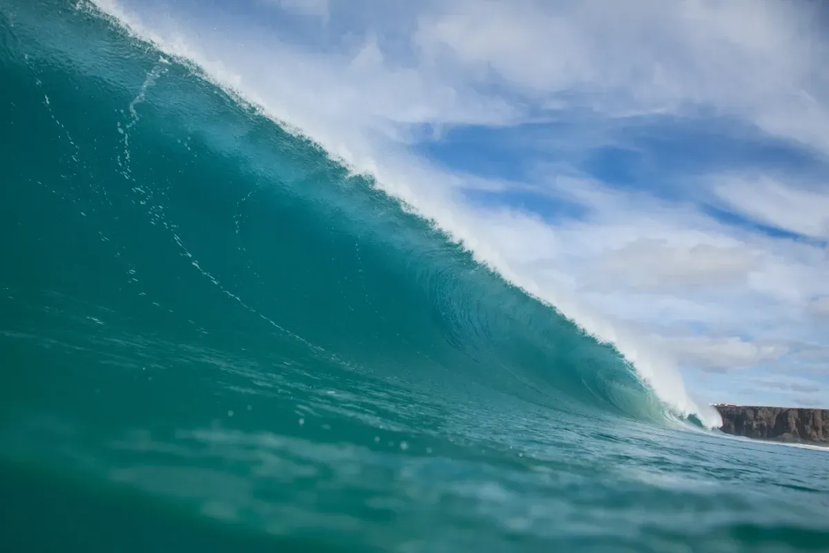 Un primer plano de una ola en el océano con un cielo azul de fondo.