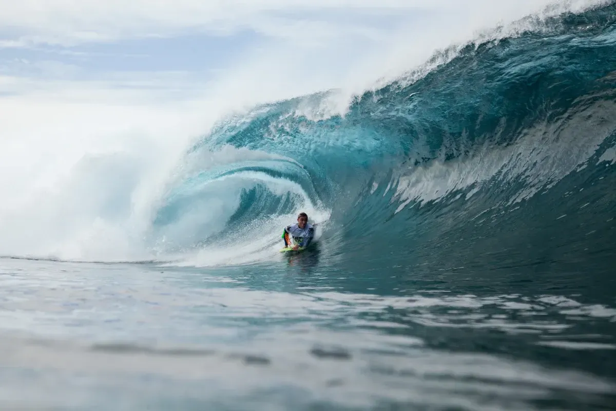 Un hombre está montando una ola en una tabla de surf en el océano.