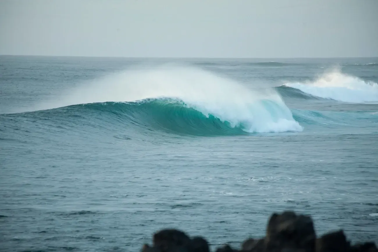 Una gran ola está rompiendo en el océano cerca de la orilla.