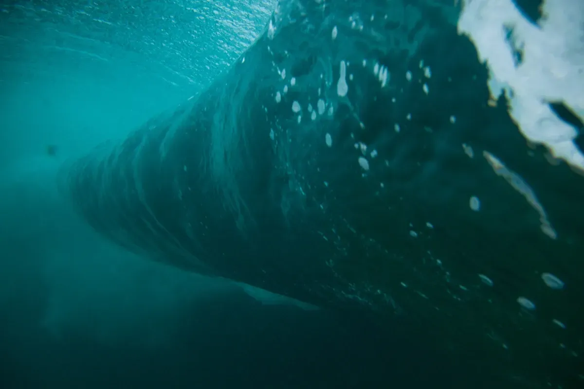 Una ola rompe en el océano y de ella salen burbujas.
