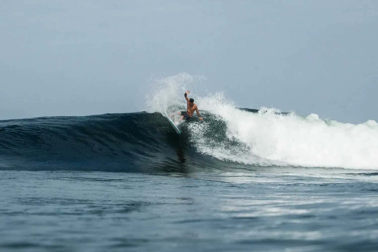 Un hombre está montando una ola en una tabla de surf en el océano.