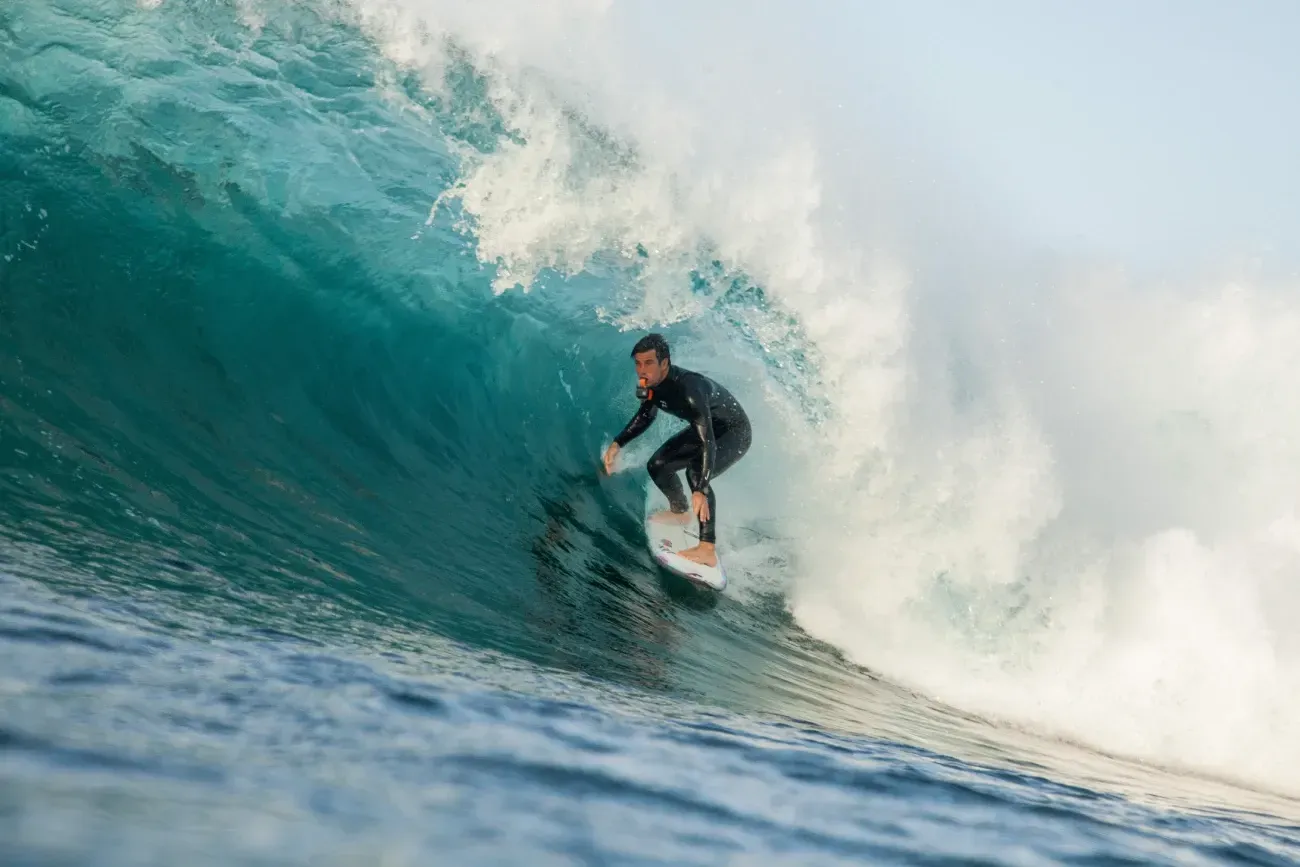 Un hombre está montando una ola en una tabla de surf en el océano.