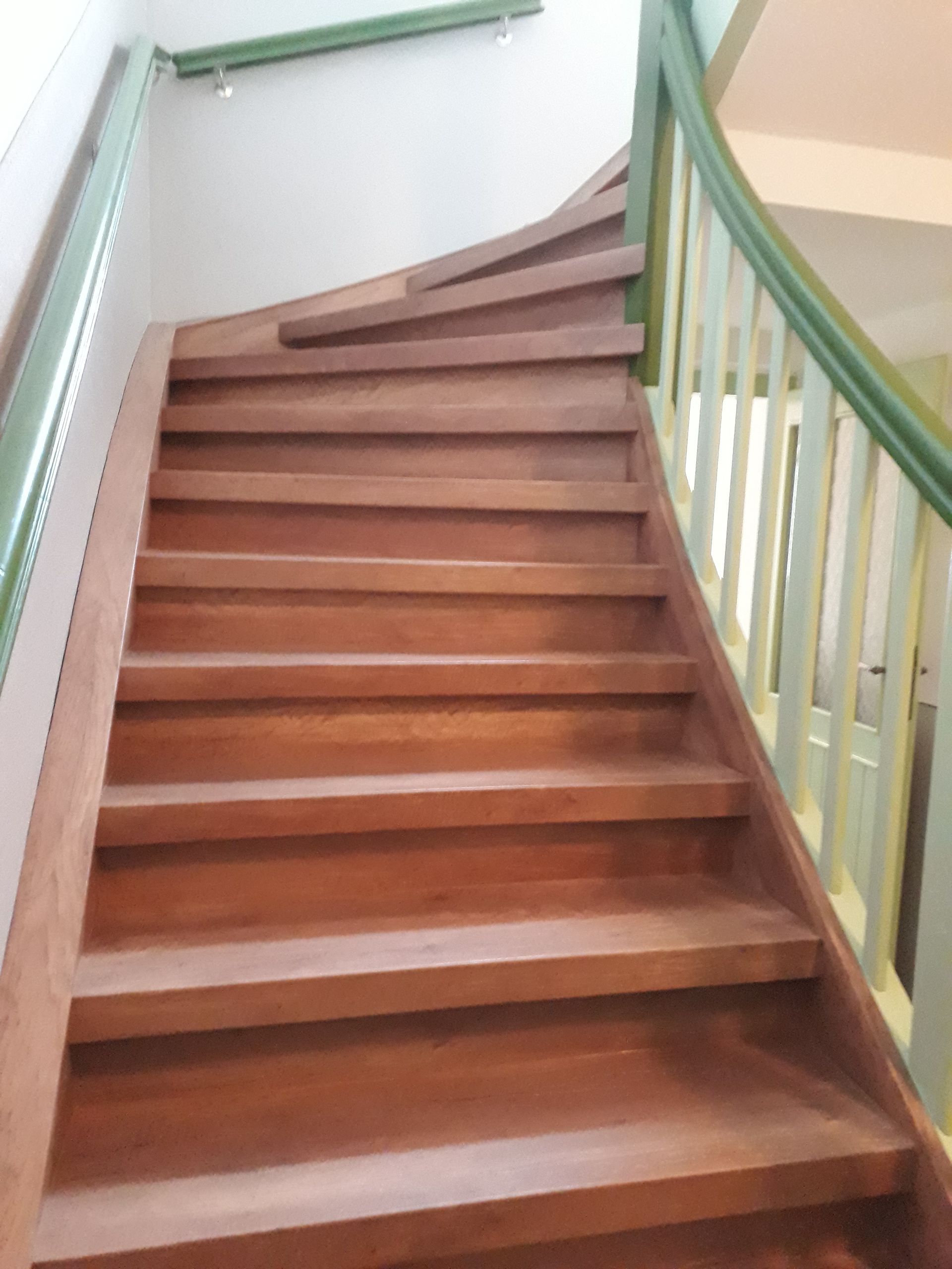 Eine braune Holztreppe mit weiß-grünem Geländer