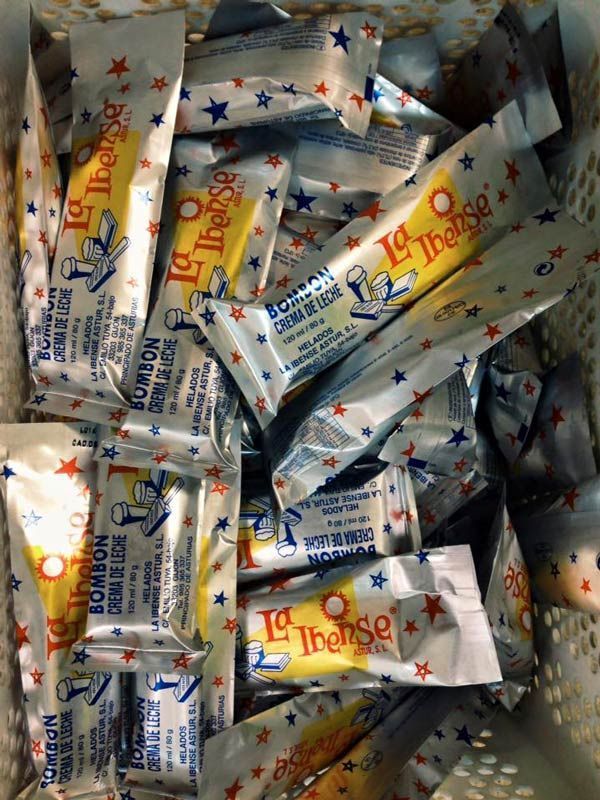 Surtido de caramelos Tootsie Roll en envoltorios plateados con letras rojas y azules, apilados en un recipiente.