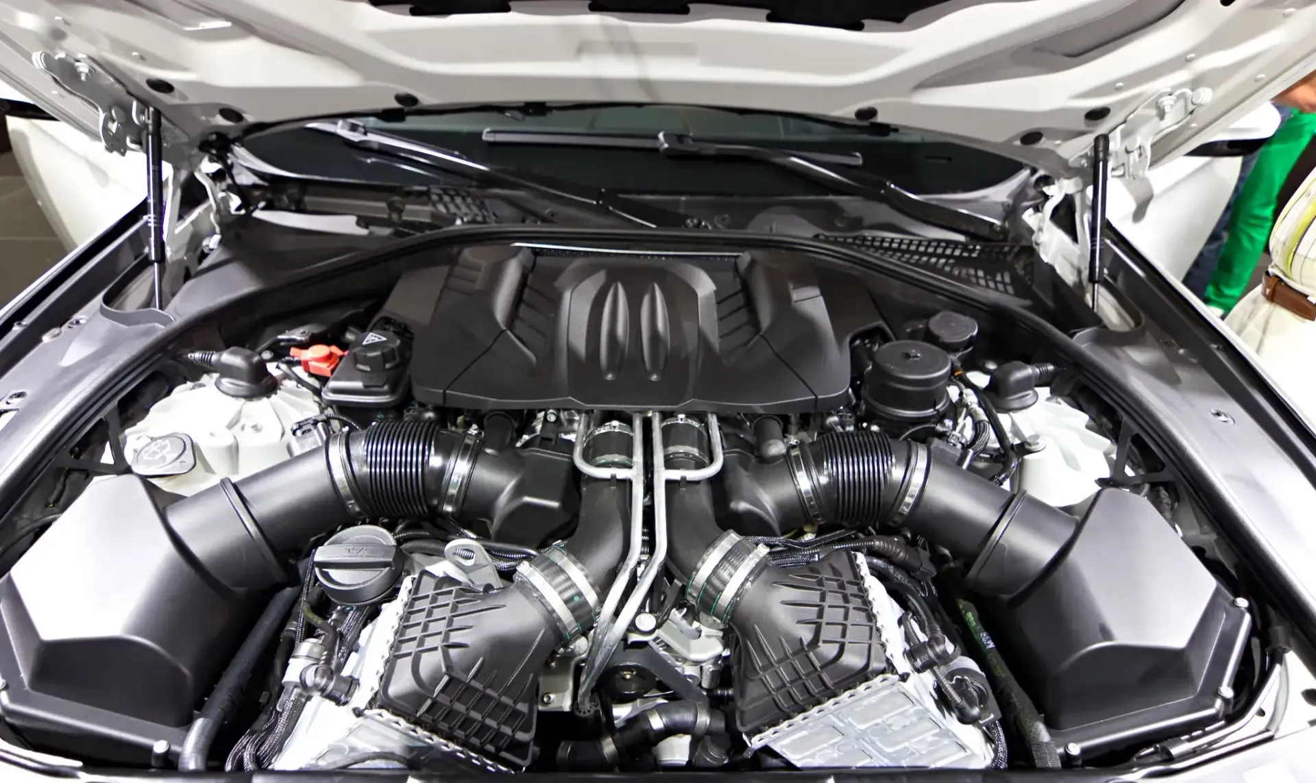 Motor negro de un coche, visto desde arriba con el capó abierto.