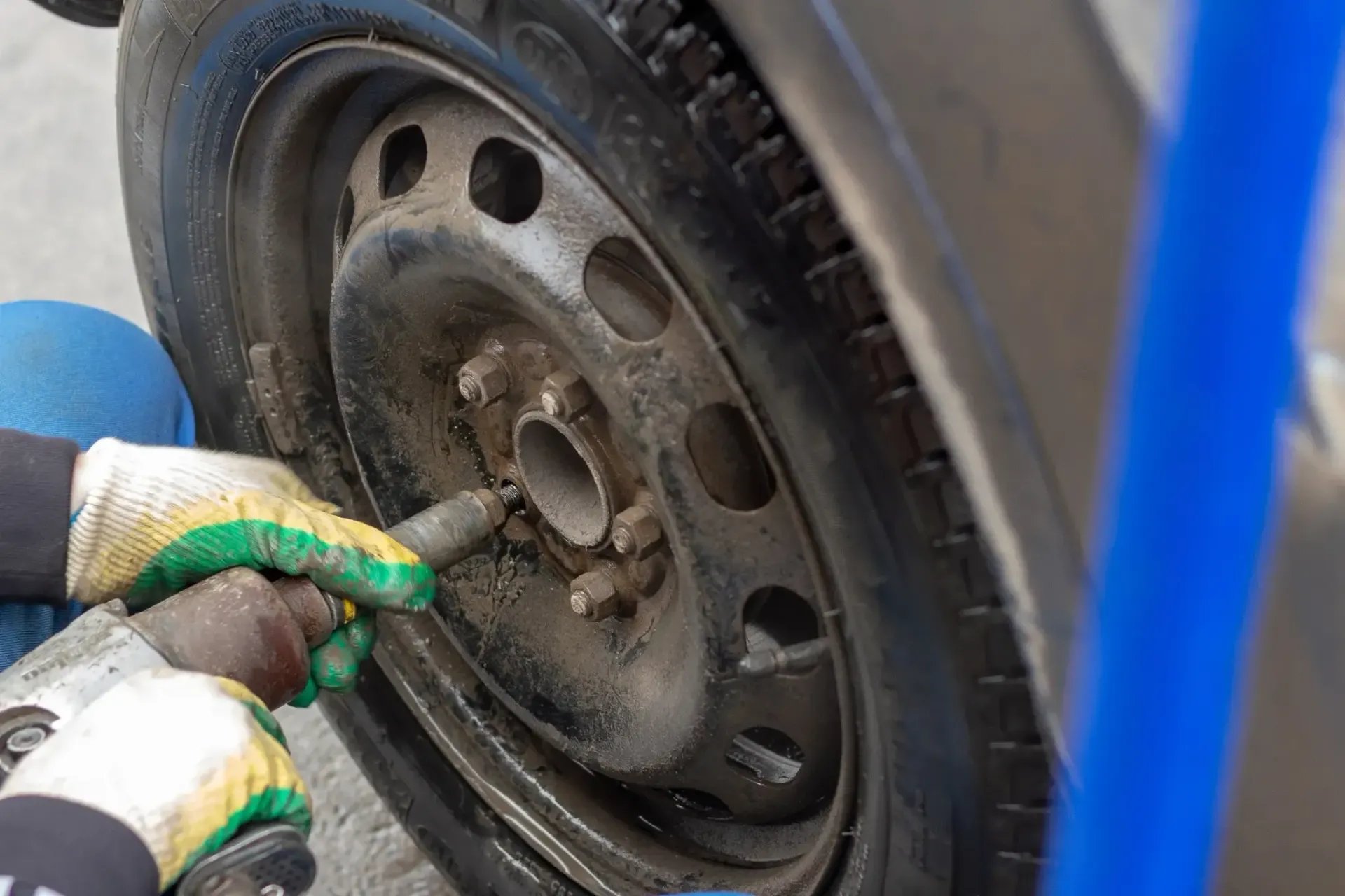 Manos en guantes de trabajo fijando un neumático a una rueda de automóvil.