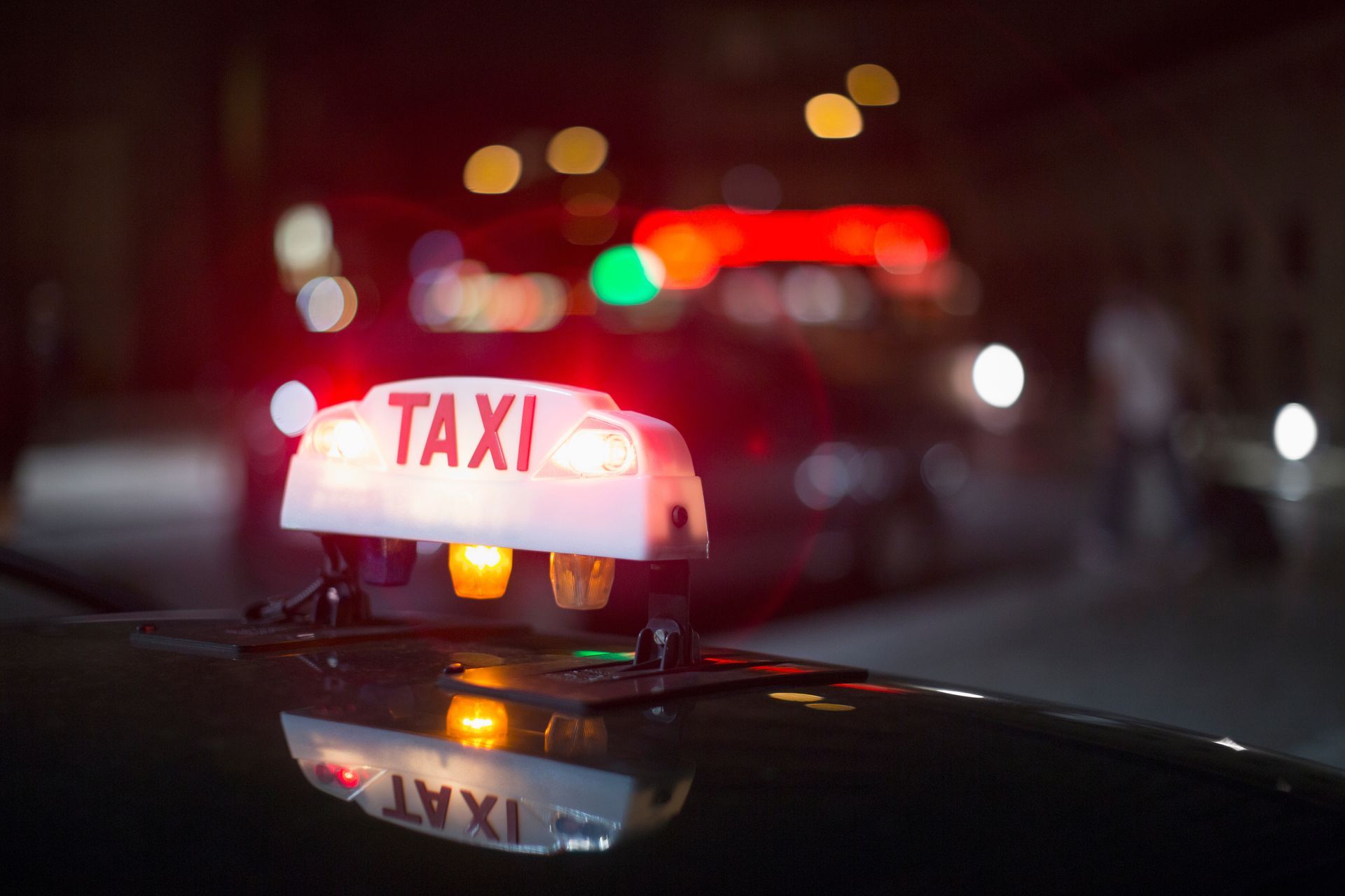 Panneau lumineux de taxi sur une voiture la nuit, avec les lumières de la ville floues en arrière-plan