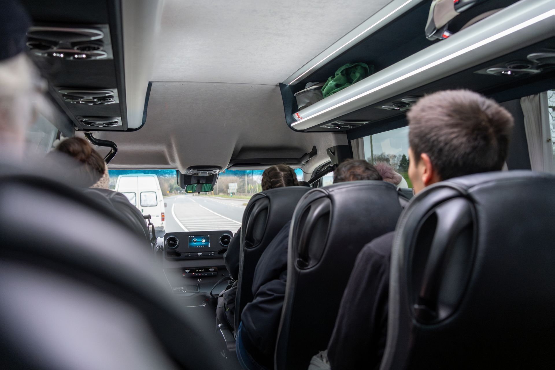 Passagers assis à l'intérieur d'une camionnette, vus de l'arrière vers le pare-brise avant.