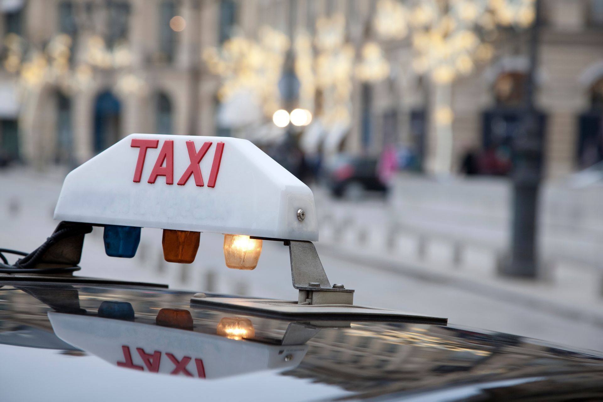 Panneau de taxi sur le toit d'une voiture dans une rue de la ville, avec des bâtiments flous en arrière-plan.