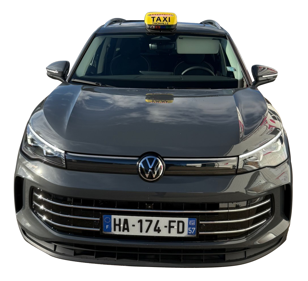 Taxi Volkswagen gris avec un panneau « TAXI » sur le toit. Plaque d'immatriculation française « HA-174-FD ».