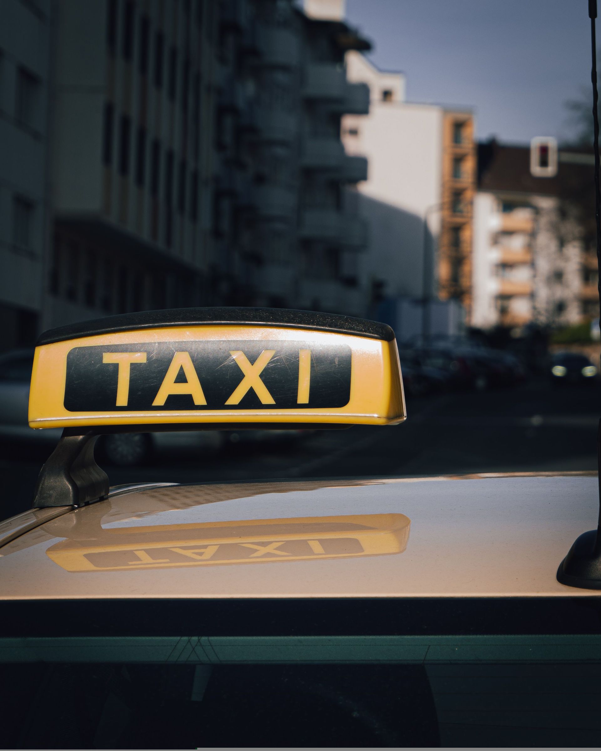 Panneau jaune de taxi sur le toit d'une voiture dans une rue de la ville au crépuscule