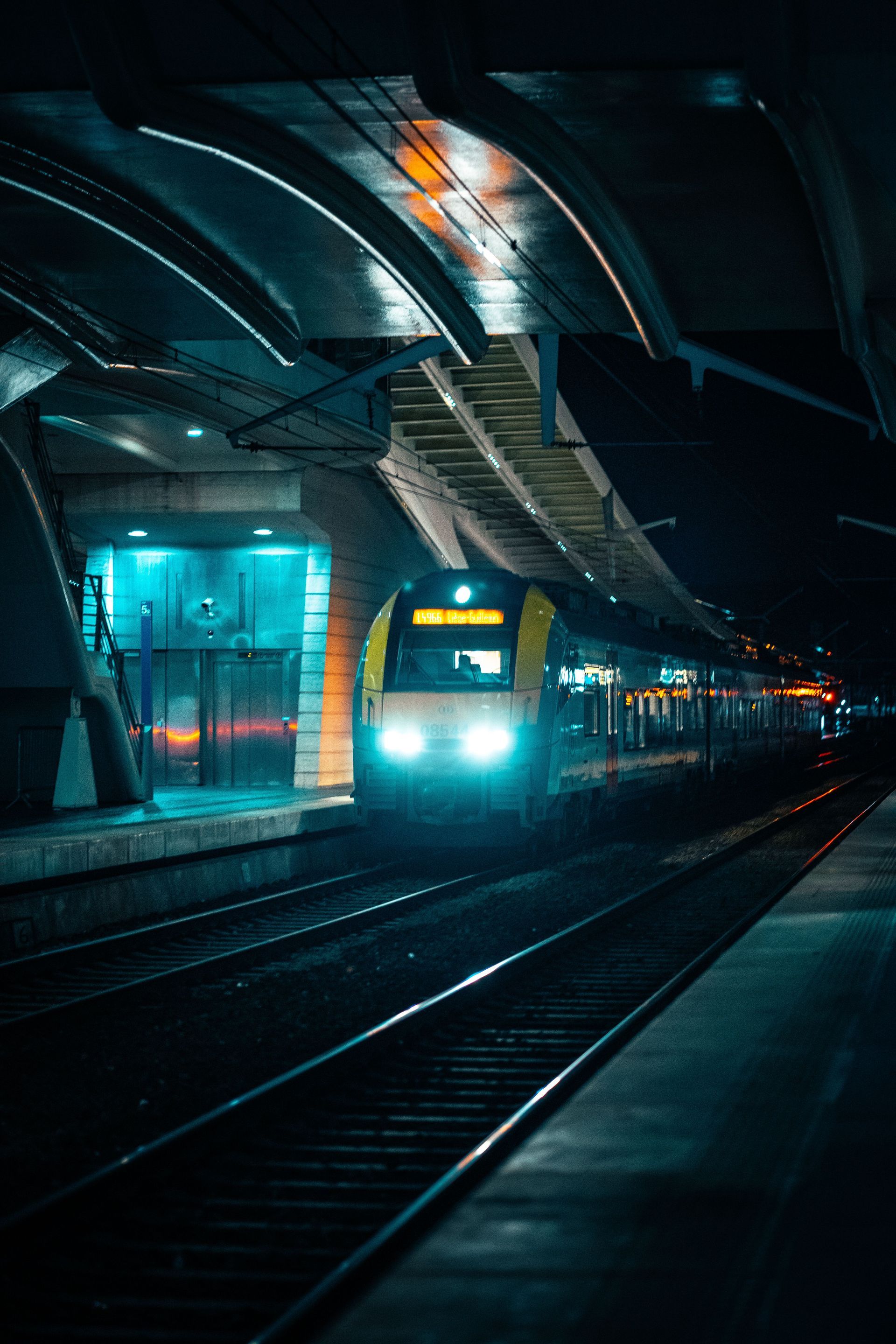 Quai de métro éclairé en bleu, un train approchant dans une station souterraine sombre