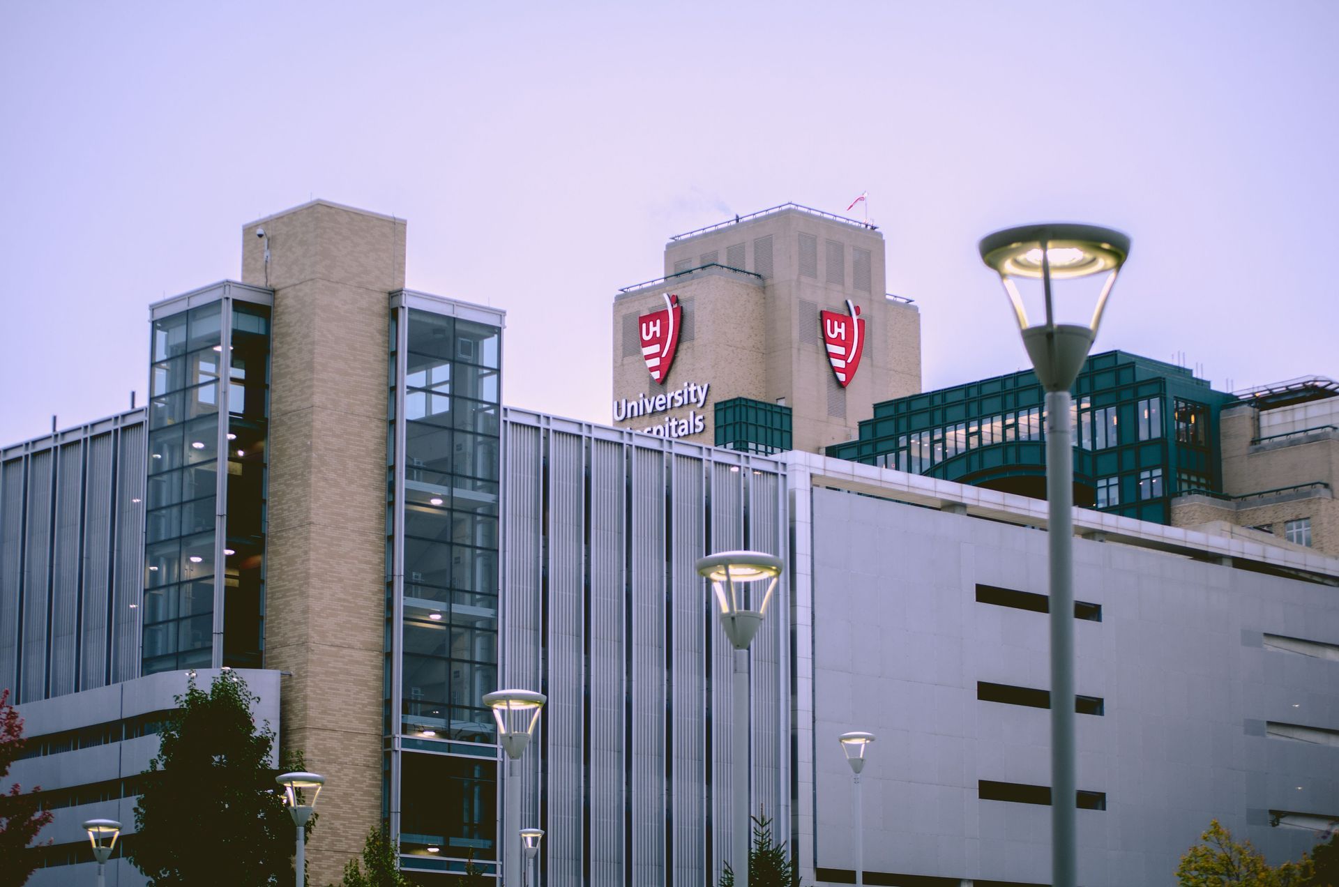 Bâtiment moderne au crépuscule, avec logos et lampadaires illuminés en rouge devant