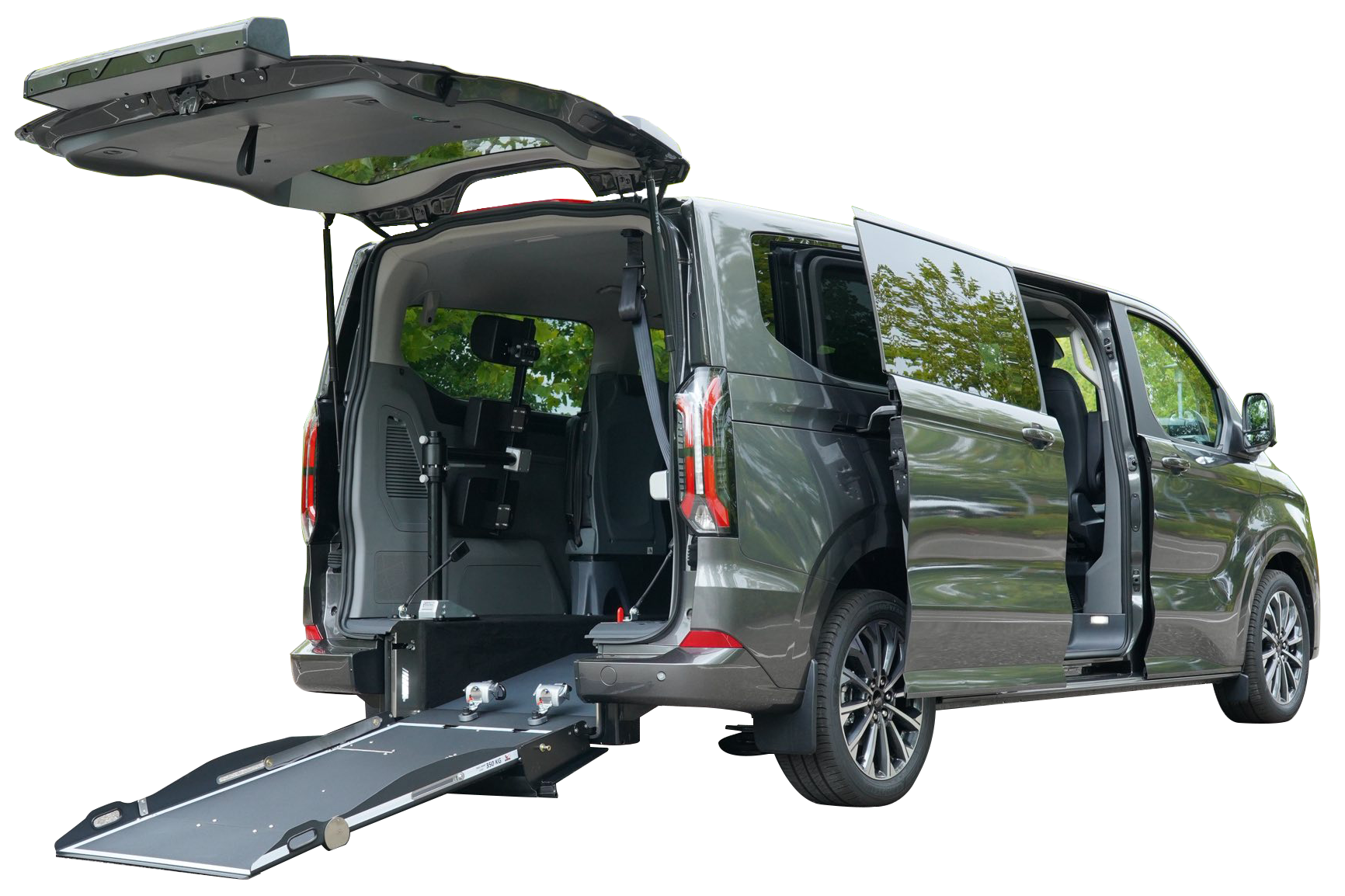 Fourgonnette accessible aux fauteuils roulants avec rampe et portes ouvertes, extérieur gris, située dans ce qui semble être un cadre naturel.