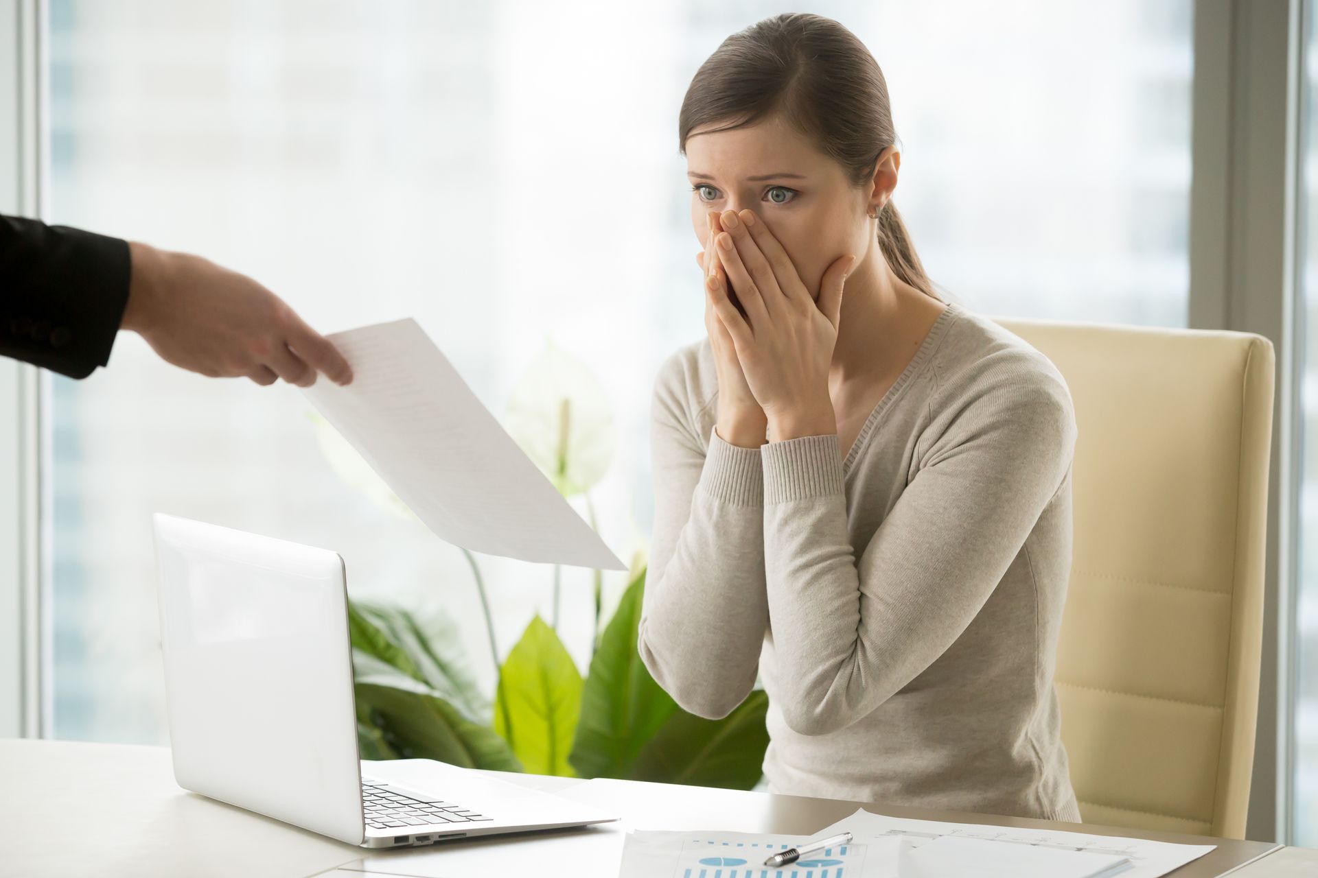 Une femme se cache la bouche devant une feuille.