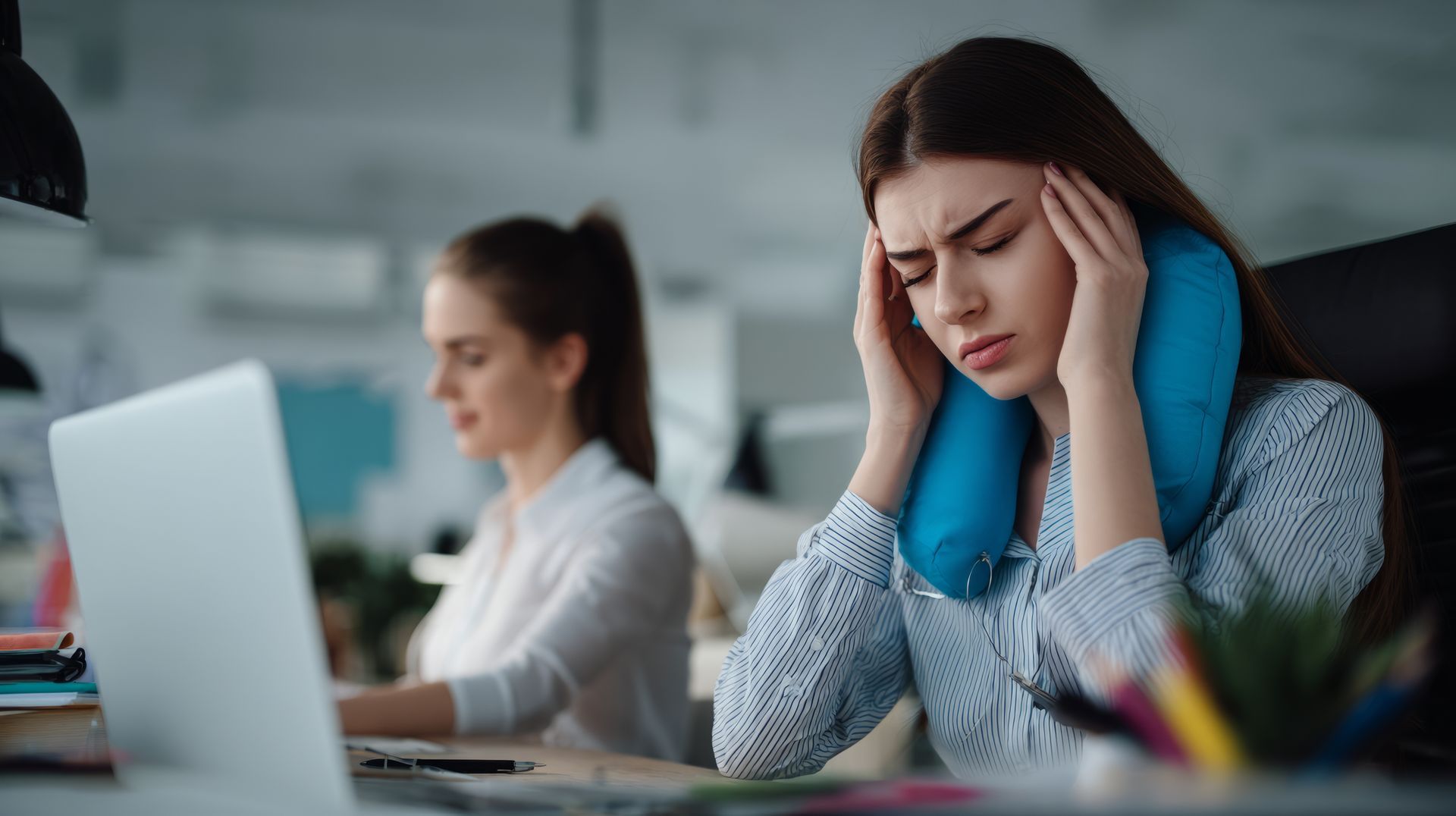 Une femme se touche les tempes au bureau.