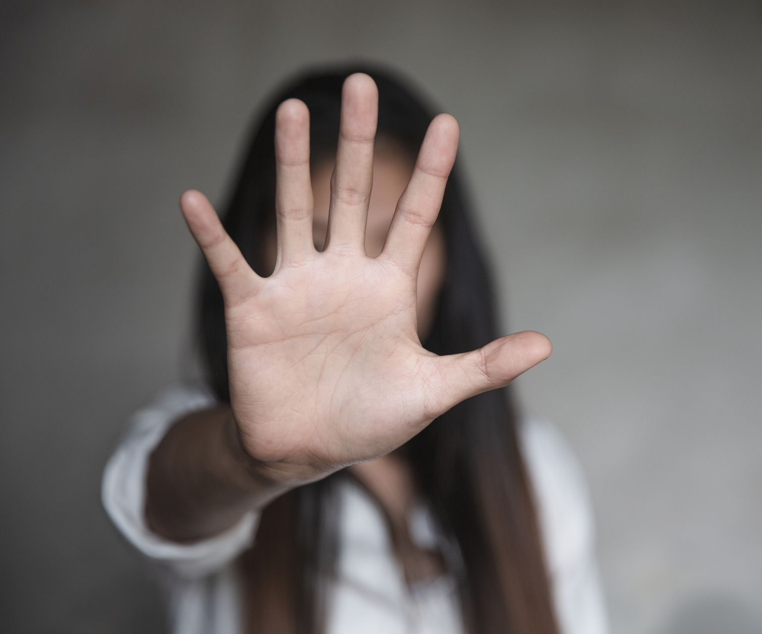 Une femme cache son visage avec sa main.