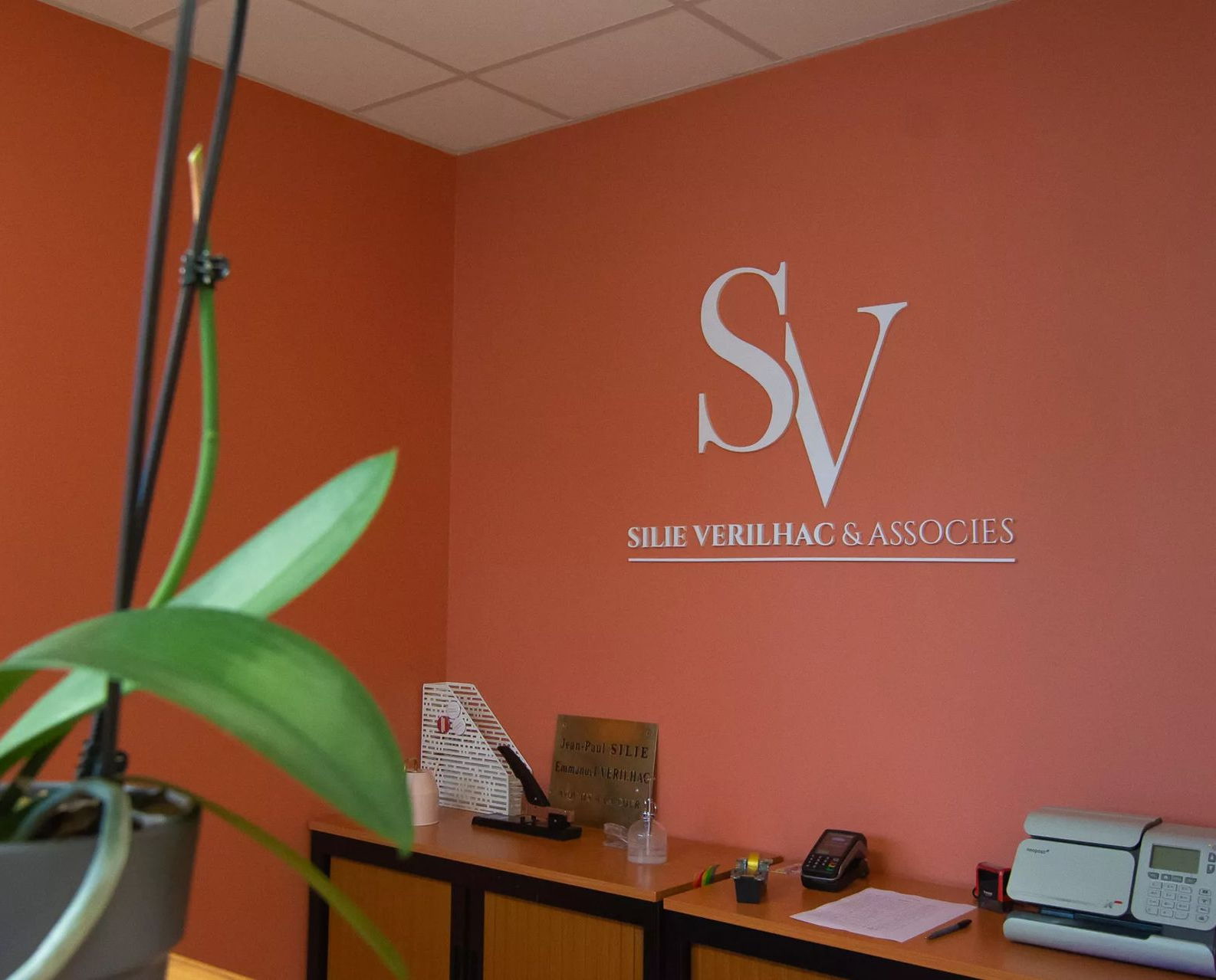 Le logo de Silie Verilhac & Associés sur un mur orange.